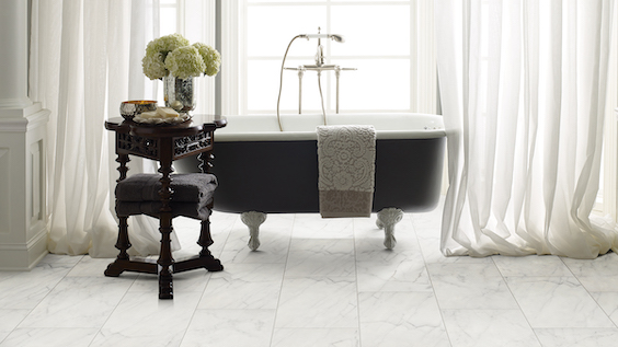 marble tile flooring in a bright and elegant bathroom with a stand alone tub and floor length sheer white drapes